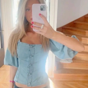 Ljusblå jeanstopp med puffärmar - LÅNAD BILD!!!Trendig ljusblå jeanstopp i jeansmaterial med puffiga korta ärmar och markerad midja💕liknande som på bilden, men ej samma💕 toppen är perfekt för en snygg och välfixad outfit 💕storlek xs/s💕tyvärr vet jag ej märket 💕