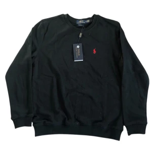Svart sweatshirt från Polo Ralph Lauren - Svart sweatshirt från Polo Ralph Lauren med rund halsringning och klassisk röd broderad logga på bröstet. Tröjan har långa ärmar och ribbade muddar vid ärmslut och nederkant. Perfekt för en stilren och avslappnad look.