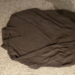 Oscar Jacobson halfzip  - Säljer en brun långärmad tröja från Oscar Jacobson i storlek S. Tröjan har halv dragkedja vid halsen och är tillverkad i ett mjukt material. Perfekt för lager-på-lager och stilrena outfits. För mer frågor så är det bara och höra av sig!