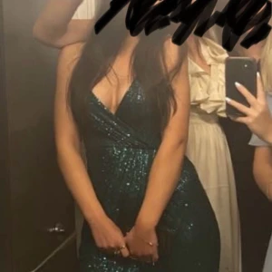 Grön långklänning  - Säljer en lång grön paljettklänning från Bubbleroom med v-ringning och omlottliv. Klänningen har en dragkedja i ryggen och är endast använd en gång🩷