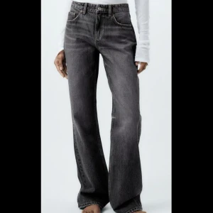 Raka lågmidjade jeans från Zara - Säljer ett par mörkgrå jeans från Zara med raka ben och klassisk femficksdesign. Jeansen har normal passform och stängs med dragkedja och knapp. Jeansen är lågmidjade! Dock är den slitna i nedkant då den är väldigt långa i benen så perfekt att klippa av och så är de perfekt till marken / sko kanten om du är runt 160 cm lång!
