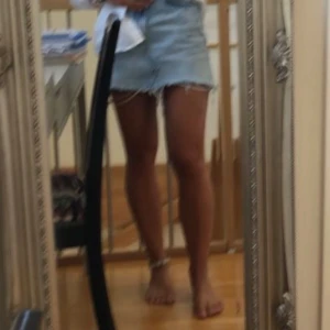 Kort Jeanskjol från ZARA  - Säljer en klassisk ljusblå jeanskjol från ZARA med rå, fransig nederkant och femficksmodell. Kjolen har knapp och dragkedja framtill samt bälteshällor. Perfekt för en avslappnad stil. Kort jeanskjol / mini kjol från Zara i storlek xs, säljer pga förliten.