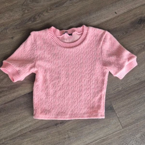 Rosa stickad crop topp från ZARA - Superfin rosa stickad crop topp från ZARA med korta ärmar och ribbade kanter vid halsringning och ärmslut. Perfekt för en söt och trendig look. Mjukt material och diskret mönster i tyget. Aldrig använd passar även nån med storlek s