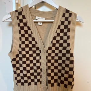 Rutig väst - Stickad rutig väst från monki💕Använd fåtal gånger och i mycket bra skick, inga defekter. Västen har ett rutigt mönster framtill och helt enfärgad på baksidan. Västen är i färgerna brun och beige. Den har även knappar som gör att man kan bära den stängt eller öppet. Skriv gärna vid frågor eller funderingar☺️