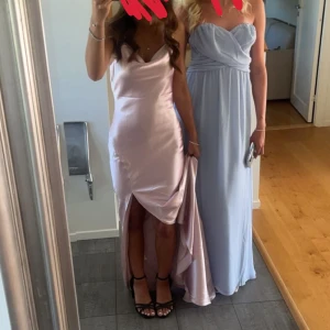 Ljusrosa långklänning med slits och öppen rygg - Elegant ljusrosa långklänning i satin med smala axelband. Perfekt för bal eller festliga tillfällen. Använd 1 gång