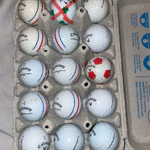 Golfbollar - En äggkartong fylld med olika golfbollar, främst av märket Callaway. Perfekt för dig som gillar golf och vill ha extra bollar till träning eller spel. Några bollar har unika mönster och färger, vilket gör dem lätta att känna igen på banan.