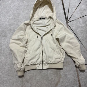Beige hoodiejacka från Zara - Säljer en beige hoodiejacka från Zara i storlek S. Jackan har dragkedja framtill, två fickor och ribbade muddar vid ärmslut och midja. Perfekt för för alla säsonger med en avslappnad passform och mjukt bomullsmaterial.