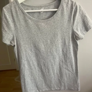 Grå basic t-shirt - En enkel och stilren grå t-shirt med rund halsringning och korta ärmar. Perfekt att matcha med jeans eller shorts för en avslappnad look. Gjord i mjukt bomullsmaterial för extra komfort.