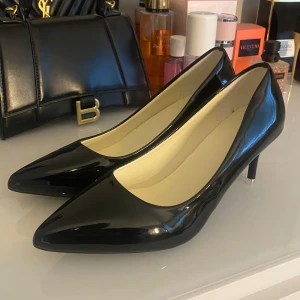 Svarta lackade pumps med klack - Klassiska svarta pumps i glansigt syntetmaterial med spetsig tå och smal klack. Aldrig använda pga dem ej passar 💗