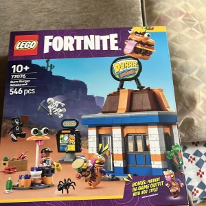 LEGO Fortnite Durr Burger Restaurant 77076 - Bygg det ikoniska Durr Burger-restaurangen från Fortnite med detta LEGO-set! Perfekt för dig som gillar gaming och kreativa byggutmaningar. Innehåller 546 bitar och roliga minifigurer. Passar både Fortnite- och LEGO-fans från 10 år och uppåt.