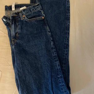 Blå jeansbyxor från TWIG - Säljer ett par klassiska blå jeansbyxor från TWIG med raka ben och normal passform. Jeansen har fem fickor, bälteshällor och stängs med dragkedja och knapp. Perfekta till vardags och enkla att matcha med olika toppar.