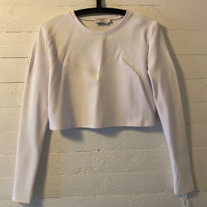 Vit croppad långärmad topp från NA-KD x Hanna Schönberg - Vit croppad långärmad topp från NA-KD i samarbete med Hanna Schönberg. Endast använd ett par gånger. Snörning längs ärmarna. 