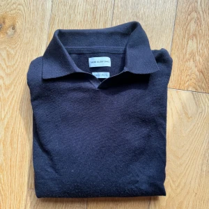 Svart pikétröja från These Glory Days - Klassisk svart pikétröja från These Glory Days med krage och långa ärmar. Tröjan är tillverkad i ett mjukt material och har en stilren, tidlös design som passar perfekt till många olika outfits. Storlek M