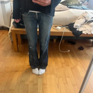 Blå lågmidjade bootcut jeans från Lee - Lågmidjade jeans från lee. Snygga, köpta second hand. Dom har lite slitningar men de mesta är tvätten på byxorna. Lite slitna vid hälarna. Passar bra i längd på mig som är 165. Skulle säga att dom är mellan 34-36.