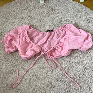Rosa croppad topp/Bolero - Säljer en söt rosa croppad topp/Bolero från BikBok med puffärmar och knytning framtill. Toppen har en v-ringad design och är perfekt för varma dagar. Superfin att styla med både kjol och jeans! Använd en gång!