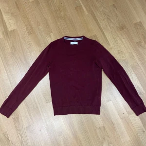 Vinröd tröja från Pier One - Säljer en stilren vinröd tröja från Pier One. Tröjan har rund halsringning och långa ärmar, perfekt för lager-på-lager. Passar både till jeans och chinos för en clean look.