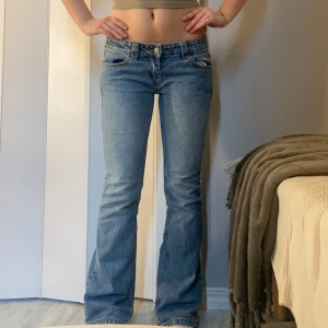 Ljusblå bootcut jeans - Snygga ljusblå jeans med bootcut passform och klassisk femficksdesign. Jeansen har låg midja och stängs med knapp och dragkedja framtill. 