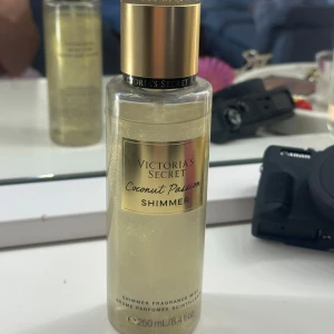 Victoria's Secret Coconut Passion Shimmer - Shimmer mist från Victoria's Secret i doften Coconut Passion. Ger huden en skimrande finish med en tropisk doft av kokos och vanilj. Flaskan är transparent med guldigt lock och etikett, innehåller 250 ml. Köptes i USA. 100% original.