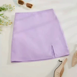 Ljuslila kortkjol med slits - Säljer en söt ljuslila kortkjol med liten slits framtill. Kjolen har en enkel och stilren design, perfekt att matcha med olika toppar. Materialet känns mjukt och lätt, och kjolen har en rak passform.