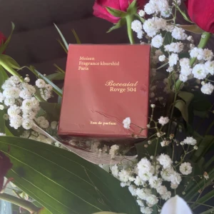 Boccaial Rouge 504 Eau de Parfum från Moisen Fragrance Khurshid Paris - Säljer en lyxig parfym Boccaial Rouge 504 från Moisen Fragrance Khurshid Paris. Förpackningen är röd med gulddetaljer och har en elegant design med husmotiv på sidan. Eau de parfum-variant som passar dig som gillar exklusiva dofter.