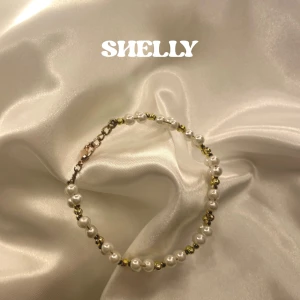 Shelly bracelet - Ett elegant armband med vita pärlor och små guldfärgade detaljer. Armbandet är gjort på Messing bas med smyckeslås för en enkel på- och av tagning.