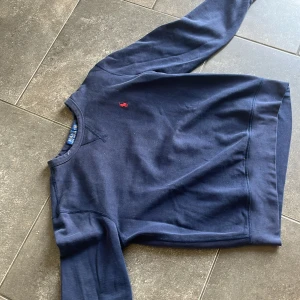 Mörkblå sweatshirt från Polo Ralph Lauren - Mörkblå sweatshirt från Polo Ralph Lauren med klassisk rund halsringning och liten röd broderad logga på bröstet. Tröjan har långa ärmar och är tillverkad i mjuk bomull. Perfekt för en avslappnad stil. För mer frågor kp den är 100 procent äkta också. 