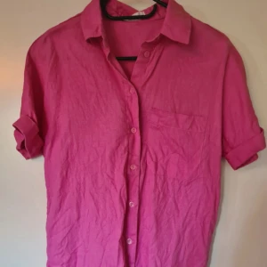 Rosa linneskjorta med kort ärm - Säljer en snygg rosa skjorta i linne med korta ärmar och klassisk krage.