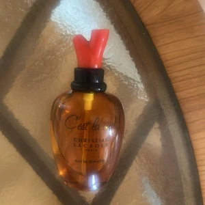 C'est la Vie Eau de Toilette från Christian Lacroix - En elegant parfymflaska i hjärtformad flaska Sparsamt använd. 50 ml Eau De Toilette. Vintage från 1990. Märkt med 'C'est la Vie' och 'Christian Lacroix Paris'.