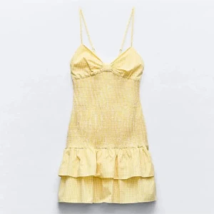 Gul rutig volangklänning🩷 - Söt gul kortklänning med smala axelband, volang nertill och rosett framtill. Klänningen har ett rutigt mönster och en feminin passform, perfekt för varma dagar. Storlek L men väldigt små i storlek !