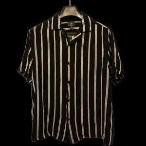 Svartvit randig skjorta - Svartvit randig skjorta från H&M. Skjortan har korta ärmar, klassisk krage och knäppning framtill. Strl S