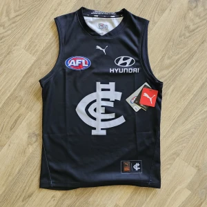 Svart AFL fotbollströja från Puma - Säljer en svart AFL fotbollströja från Puma med stora vita tryck, inklusive klubbmärke och sponsorloggor. Tröjan är ärmlös och har rund hals. Se Bild 4&5 för orginalpris samt lappar osv.