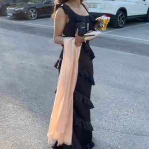 Svart balklänning  - Denna har jag haft på mig en enda gång - förra året på min studentbal💗Pris kan förhandlas! Säljer en svart långklänning med volangdetaljer och smala axelband. Klänningen har en elegant och flowy siluett, perfekt för speciella tillfällen. Materialet ser glansigt ut. Säljer även klackar om det behövs!