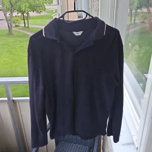 Mörkblå långärmad pikétröja med krage - Säljer en mörkblå långärmad frotté pikétröja från East West. Tröjan har klassisk krage och diskret vit kant vid kragen. Perfekt för en stilren och avslappnad look. Köpt.på Brothers i butik