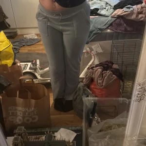 Ljusblåa byxor från Juicy Couture - Säljer ett par ljusblåa byxor från Juicy Couture med normal passform och hög midja. Byxorna har snörning i midjan och fickor med lock och knapp bak. Mjukt material som känns skönt mot huden. OBSS har defekter som ni kan se på bild 4-5