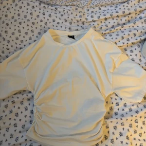 Vit croppad topp med rynkade detaljer från Gina Tricot - Säljer en vit croppad topp från Gina Tricot i storlek XS. Toppen har korta ärmar och rynkade detaljer på sidan som ger en snygg passform. Nypris: 260