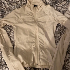 Vit jacka med dragkedja från Gina Tricot - Säljer en stilren vit jacka från Gina Tricot i storlek S. Jackan har hel dragkedja framtill, hög krage och lång ärm. Perfekt för lager-på-lager och enkel att matcha med olika outfits. Använd 1 gång 