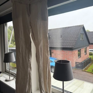 Beiga linnebyxor med normal passform - Säljer ett par beiga linnebyxor med raka ben och låg midja. Byxorna har bälteshällor, knapp och dragkedja framtill. Perfekta för en avslappnad och stilren look. Dem ser skrynkliga ut då de aldrig är använda och legat i en låda. Men jättefina på säljer pågrund av att de har blivit för stora