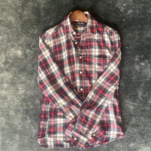 Rutig skjorta från Dressmann - Säljer en klassisk rutig skjorta från Dressmann i rött, blått och vitt. Skjortan har lång ärm, knappar framtill och en mjuk bomullskänsla. Perfekt för dig som gillar en tidlös stil med lite färg.