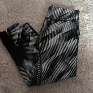 Nike träningstights - Säljer ett par Nike leggings i svart och vitt. De är tighta och perfekta för träning, med bekväm passform och fuktavvisande material. Storlek S