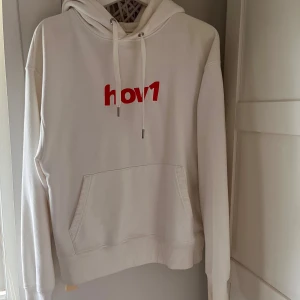 Hov1 Hoodie - Vit hoodie med rött hov1-tryck på bröstet. Två små fläckar längst ner men inget som syns om man inte kollar nära! Annars i väldigt bra skick och nästan helt oandvänd! 