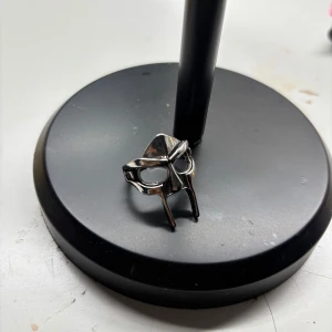 Silverfärgad ring med maskmotiv - Cool ring i silverfärgad metall med ett maskformat motiv framtill, inspirerad av en ikonisk hjälm. Ringen har en unik och edgy design som sticker ut och passar perfekt för dig som gillar statement-smycken.