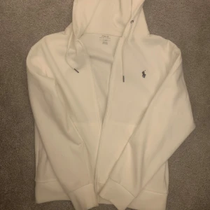 Vit Ralph louren zip - Säljer en stilren vit hoodie från Polo Ralph Lauren med dragkedja. Den är i toppenskick och är i princip oanvänd, är öppen för byten med. tveka inte att höras av vid intresse😊