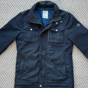 Mörkblå jacka från J.Lindeberg - Snygg svart jacka från J.Lindeberg, skick 8/10. Storlek S, hör gärna av er vid fler funderingar.