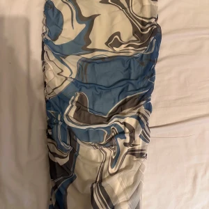 Kjol från Gina Tricot - Snygg klänning från Gina Tricot med ett abstrakt mönster i blått, vitt och grått. Klänningen har en åtsittande passform och är perfekt för att sticka ut med sin unika design. Tillverkad i ett mjukt och bekvämt material. Storlek s