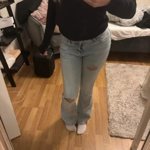 Ljusblå lågmidjade jeans med hål - Snygga ljusblå jeans med hål på knäna. De har en bootcut-stil och är lågmidjade🥰 