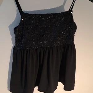 Svart paljettlinne från Gina Tricot - Snyggt svart linne från Gina Tricot med paljetter upptill och tunna axelband. Linnet har en luftig passform nedtill och justerbara axelband💞😙 kontakta för bättre bilder😙😙