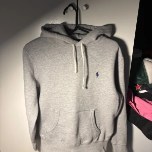   Ralph Lauren hoodie - Säljer en stilren grå hoodie från Ralph Lauren.Den har en liten broderad logga på bröstet i blått. Perfekt för en avslappnad look.