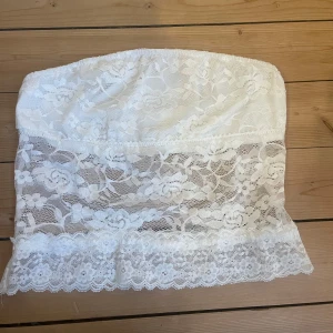 Vit spets tubtopp - Säljer en söt vit tubtopp i spets med blommigt mönster. Helt oanvänd då den tyvärr inte passade:(