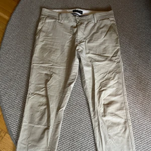 Beige chinos från Allen Solly - Snygga beige chinos från Allen Solly med en klassisk design. Byxorna har en rak passform och är tillverkade i ett bekvämt material. Använda ett fåtal gånger. Priset kan diskuteras vid snabb affär. 