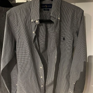 Svartvit rutig skjorta från Ralph Lauren - Snygg svartvit rutig skjorta från Ralph Lauren i slim fit. Skjortan har långa ärmar och knappar framtill. Den är broderad med den klassiska logotypen på bröstet. Perfekt för en stilren look. Tveka inte och höra av er för funderingar eller fler bilder🙌🏻, priser är ej hugget i sten. 